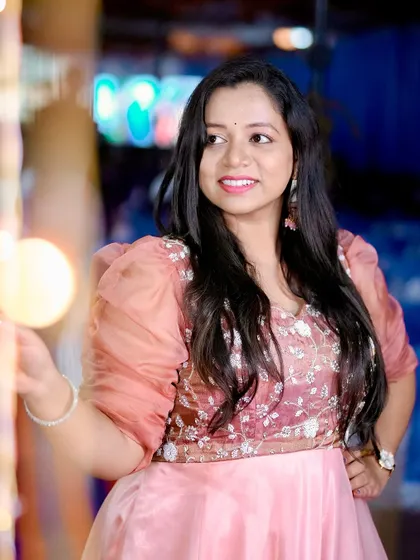 A candid shot of a client in the peach Anarkali, capturing a moment of happiness at her event.