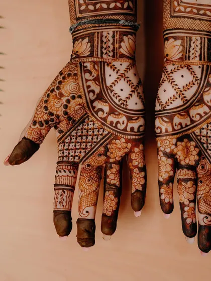 A close-up of a beautiful bridal design, focusing on the intricate floral and elephant patterns on the palm and fingers.