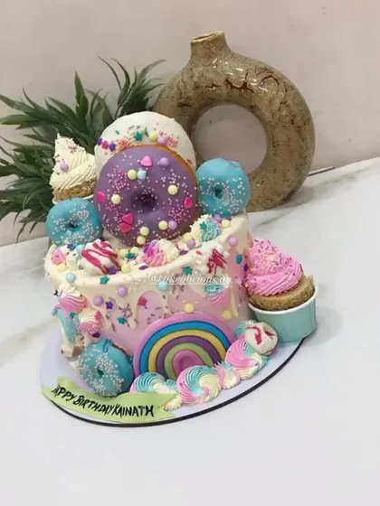 A top-down view of the candyland cake, showing the arrangement of donuts, a cupcake, and colorful meringue kisses. I love creating these over-the-top designs.