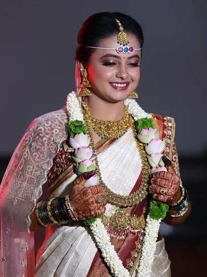 The bride holding her flower garland, her hands adorned with a deep and beautiful mehendi stain.