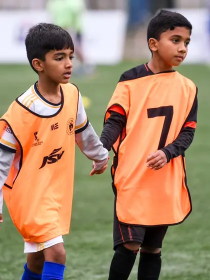 Two young players hold hands as they walk onto the pitch. The friendships made here last a lifetime.