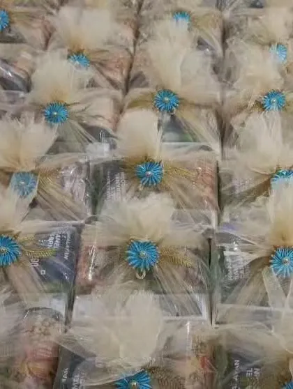 A beautiful batch of wedding favors ready to go. These hampers are elegantly wrapped in cream-colored netting with a striking blue flower, customized to the client's wedding theme.