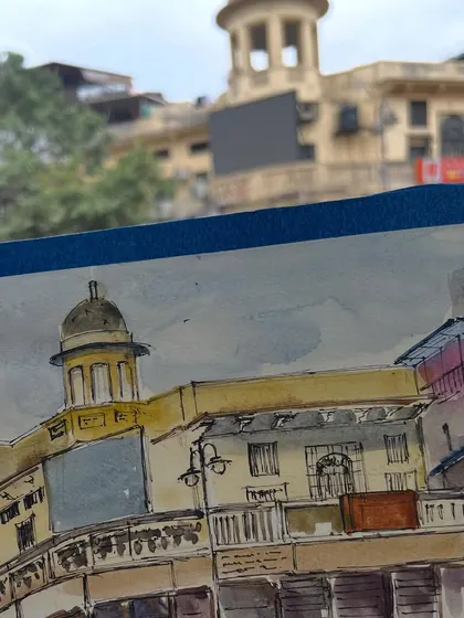 My sketchbook in action at Chandni Chowk. This view shows my watercolor sketch with the actual building in the background, capturing the moment of creation.