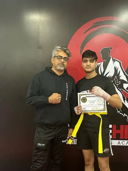 A young fighter receives his kickboxing belt, ready to continue his journey to the next level.