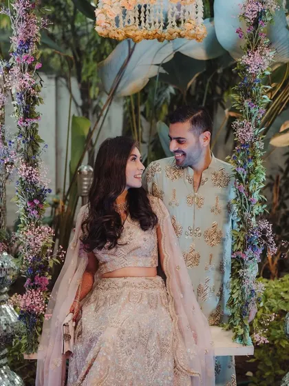 A couple enjoys a moment on a beautifully decorated floral swing. This is a perfect example of creating interactive and picturesque spots for the couple and guests.