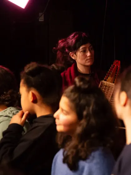 An artist from our ensemble watches a group of students during a music workshop. These educational outreach programs are a core part of our mission to make music accessible.