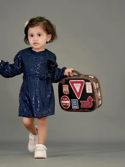 This little traveler is ready for her next journey, holding a vintage suitcase.