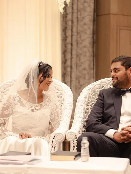 A quiet moment for the bride and groom during their Catholic wedding ceremony, seated in ornate chairs.