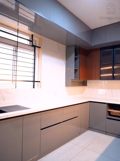 A full view of the grey and wood-themed kitchen, showcasing the white marble-look backsplash and countertop that brighten the space. The layout is designed for efficiency, with the sink and cooking areas well-defined within the L-shape.