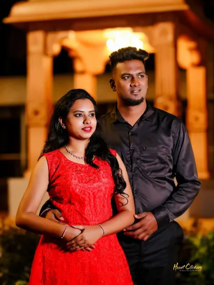 A candid portrait of a couple at night, with warm background lights creating a cozy and romantic mood.