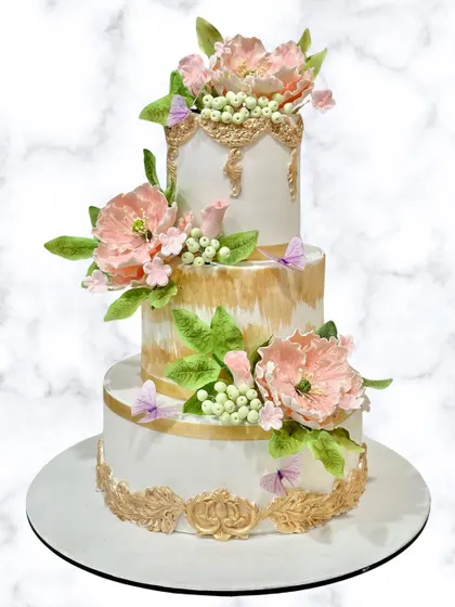 A true showstopper. This 3-tier floral wedding cake features delicate, handcrafted sugar flowers and elegant gold detailing. We work with clients to create their dream wedding cakes.