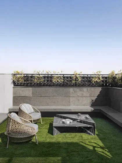 The terrace at Swatantra Residence is a full leisure floor, with open seating areas and lush artificial grass. The use of solar panels on the roof and a rainwater harvesting system promotes environmental sustainability.
