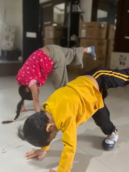 Two young children practice an animal-flow-like pose during a fun dance and movement class.