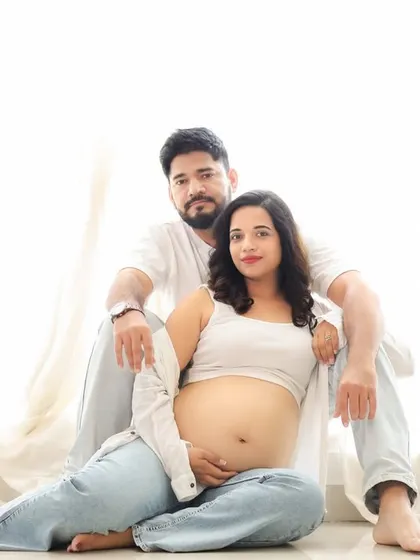 A relaxed and modern couple portrait against a clean, white background. Dressed in casual whites and denims, they create a timeless and serene image of togetherness.