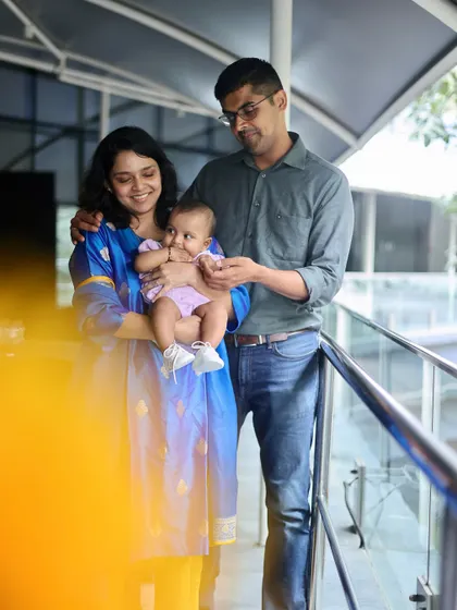 A candid family moment filled with affection. The parents are smiling at their baby, creating a natural and heartwarming scene.