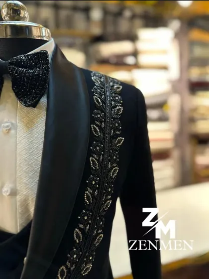 A close-up of a black tuxedo with silver leaf motifs embroidered along the lapel. The craftsmanship is evident in every stitch and bead.