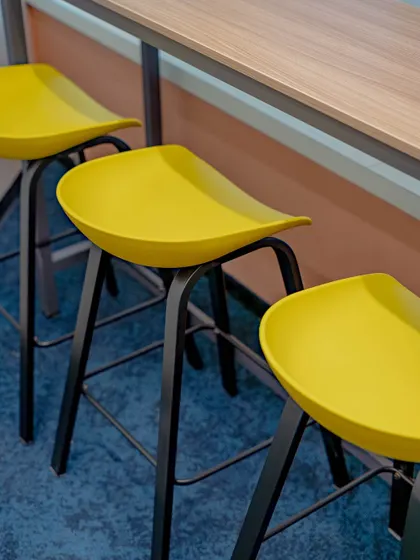 An identical shot of the yellow bar stools, highlighting their sleek black frames and modern design against the blue carpet.