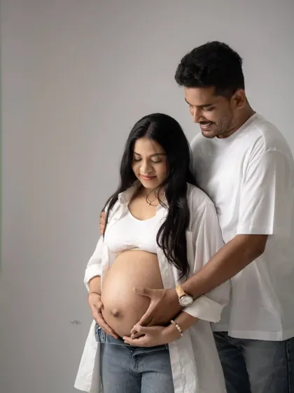 A beautiful moment of connection as the parents-to-be gently hold the baby bump together. The casual, modern styling feels fresh and authentic.