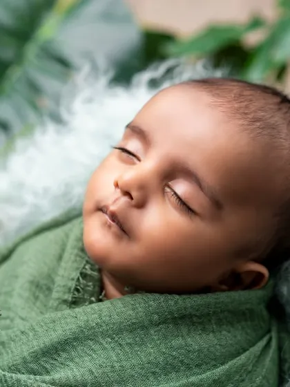 A duplicate of image 41, a serene newborn portrait in green.