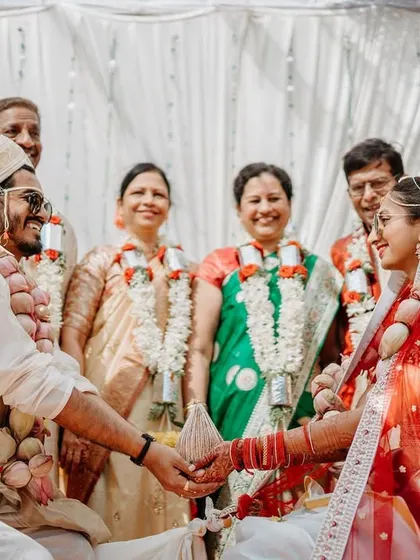 A happy family portrait during the wedding ceremony, with the couple and their parents smiling brightly.