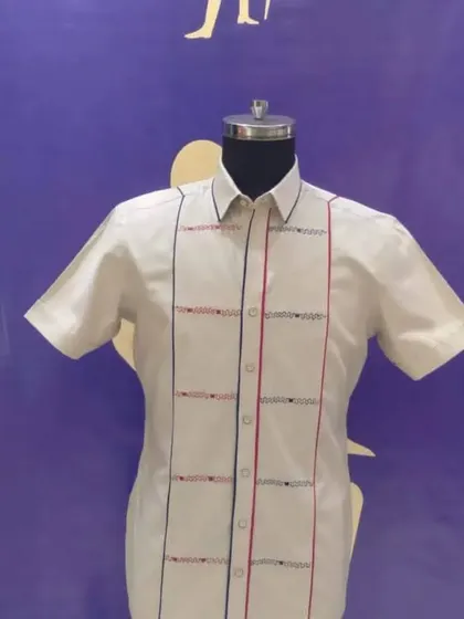 A custom half-sleeve shirt with geometric embroidery. The red and blue threadwork adds a pop of color to the white shirt, making it a unique and stylish piece.