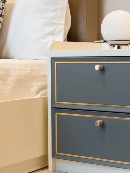 A classic bedside table design with a contemporary twist. The gray drawers are elegantly outlined with a gold-finish trim, adding a touch of glamour.