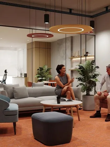 A render of a sophisticated breakout lounge, featuring a mix of plush seating, warm orange carpeting, and modern lighting. The glass partition provides a sense of openness while maintaining acoustic separation from the main office.