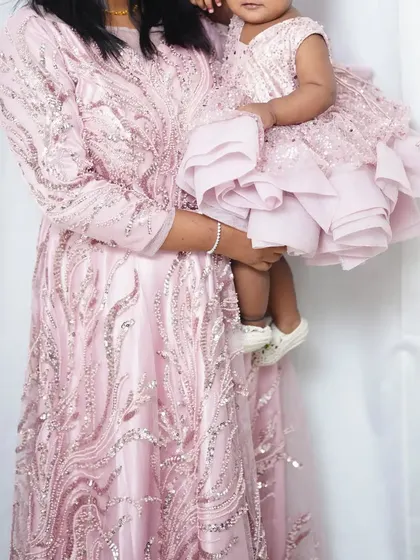 This baby pink mother-daughter gown set is perfect for a first birthday photoshoot. The intricate silver sequin work adds a touch of sparkle to your special day.