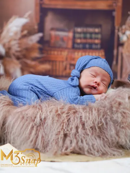 A wider view of the rustic setup, showing the baby sleeping peacefully in a tiny bed against a wooden backdrop.
