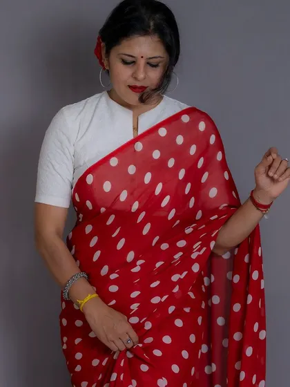 A full-view of the red polka dot saree, highlighting the simple drape and classic color combination.