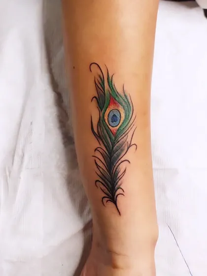 A vibrant peacock feather design was used to completely cover an old name tattoo on the forearm. The rich greens and blues, combined with fine-line details, make for a beautiful and effective cover-up that gives the client a fresh start.