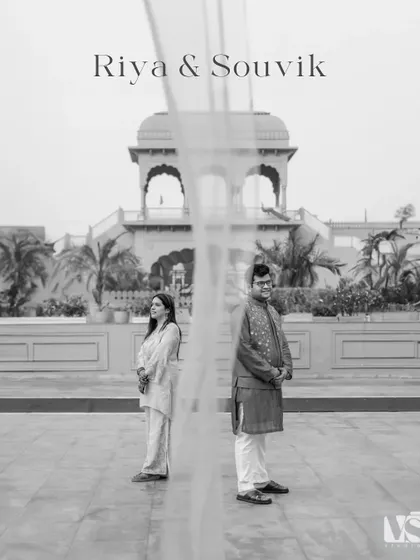 A beautifully composed black and white portrait, with a sheer curtain creating a soft, ethereal separation between the couple. This artistic shot is both modern and timeless.