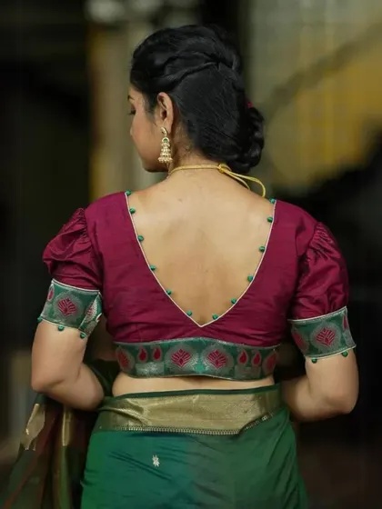 A deep red blouse with puffed sleeves and a V-back, edged with delicate beadwork.