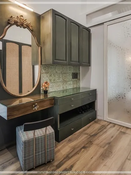 A detailed shot of the custom dressing table within the walk-in wardrobe. The pine green finish, patterned tile backsplash, and ornate mirror come together to create a personal and luxurious grooming station.