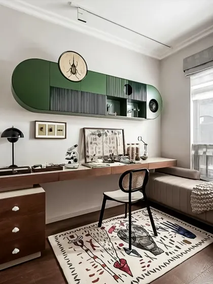 A unique and eclectic study space with custom-designed green overhead cabinets and a long wooden desk. The space is personalized with interesting art and a patterned rug.
