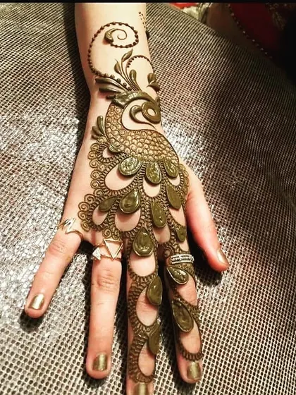 A unique and artistic take on the classic peacock mehndi. This design features a bold, 3D peacock whose feathers flow elegantly down the fingers, creating a striking and modern look that is sure to turn heads.