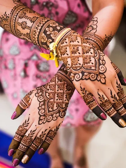 A beautiful bridal design with a focus on clean lines and varied patterns. The back of the hand features a delicate floral vine, while the arms are adorned with bands of traditional Indian motifs.