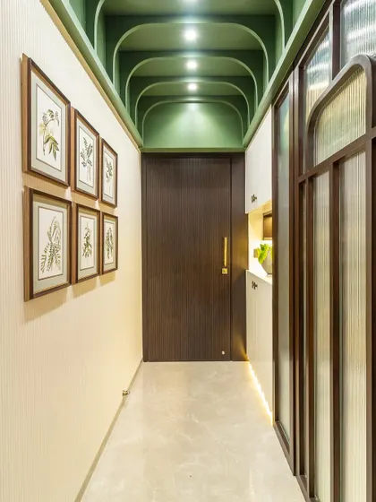 Adding a dose of color can liven up any space. The gorgeous green arched ceiling in this hallway, paired with botanical art prints, creates a vibrant and inviting passage that is full of personality.
