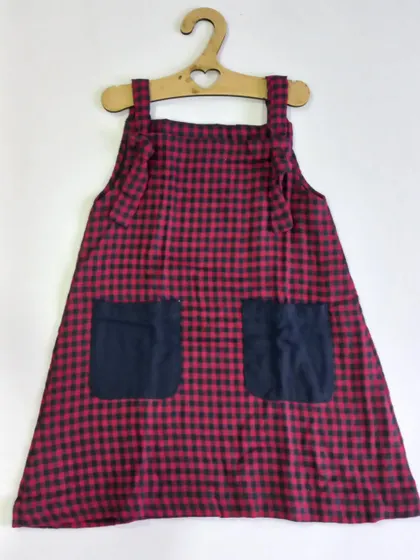 A classic knot dress in a red and black check pattern. You can just tie the knots on the shoulders and your little one is ready to go. It can be worn on its own or with a t-shirt underneath for cooler days.