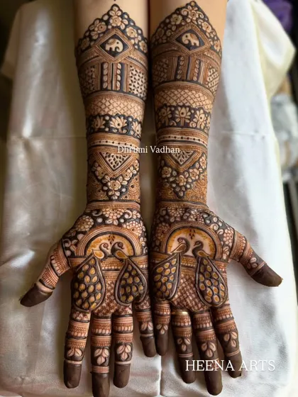 Another look at a gorgeous full-hand bridal design. The palms feature dancing peacocks, while the wrists are adorned with elephant figures, creating a story in henna.