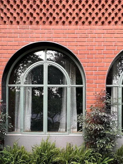 A close-up of the exterior facade, showing the detailed brick jali work above the arched windows. This traditional craft adds a layer of texture and artistry to the building's exterior.