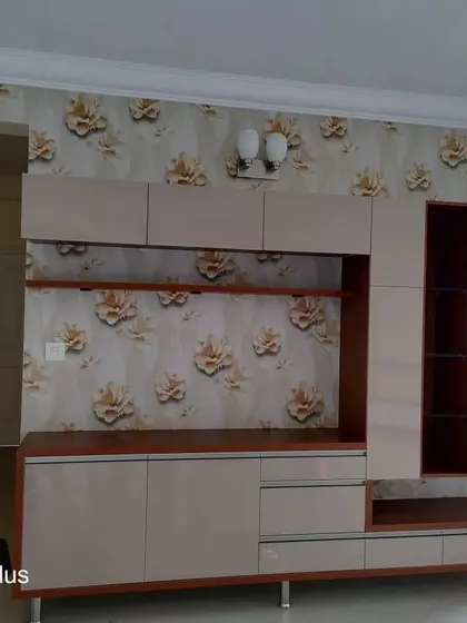 A floral wallpaper with large, golden-brown flowers installed behind a custom entertainment unit. This demonstrates how patterned wallpaper can complement and enhance wooden furniture.
