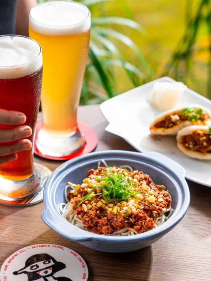 A close-up of a noodle bowl paired with two different craft beers. This shot is perfect for breweries and restaurants looking to promote their food and beer pairings.