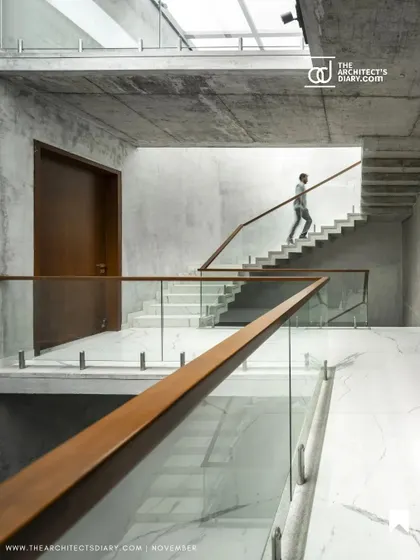 The main staircase is conceived as a social space, with wide landings and views across the atrium that encourage interaction between residents. The material palette combines raw concrete with the warmth of wood and the sleekness of glass.