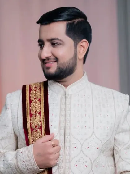 A side profile of the groom, highlighting the elegant drape of his shawl and the clean lines of his hairstyle.