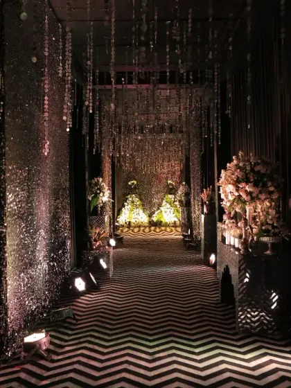 We believe the guest experience begins at the entrance. For this glamorous black and silver themed Sangeet, we designed a dramatic entryway with a chevron-patterned floor and shimmering crystal curtains, setting the stage for an unforgettable night of music and celebration.