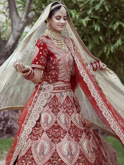 This red bridal lehenga features beautiful peacock motifs and intricate threadwork. The double dupatta style adds an extra layer of grace, and the entire set is available to rent for your wedding.