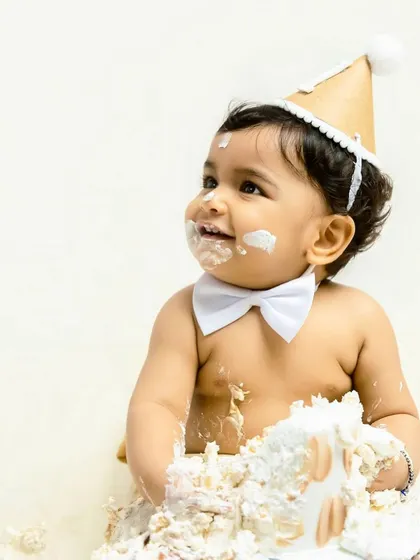 The pure, unfiltered joy of a first birthday cake smash. This little one's happy, frosting-covered smile is what these celebratory sessions are all about.