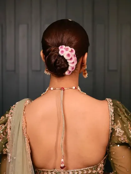 The back view of this modern floral bun. The placement of the flowers adds a pop of color and a touch of romance to the otherwise sleek and classic hairstyle.