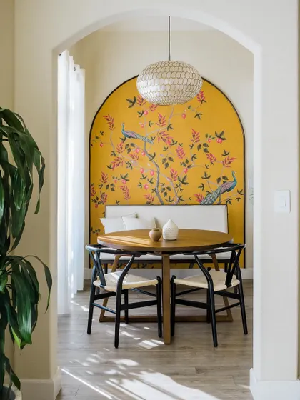 This dining nook features a stunning yellow mosaic mural that acts as a vibrant piece of art. The wishbone chairs and simple round table keep the focus on the beautiful, arched backdrop.